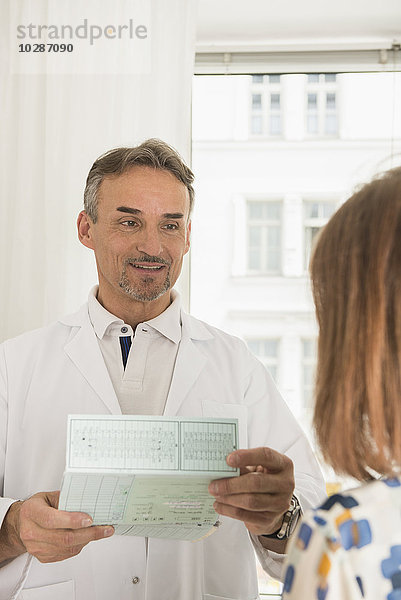 Arzt hält Krankenakte und spricht mit Patient im Krankenhaus  München  Bayern  Deutschland
