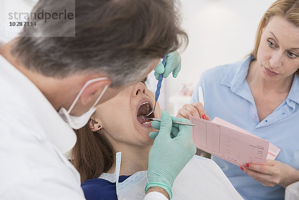 Zahnarzt  der den Patienten untersucht und den Befund der Assistentin diktiert  München  Bayern  Deutschland