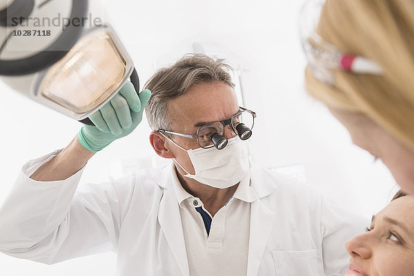 Nahaufnahme eines Zahnarztes  der einen Patienten mit Lupen auf einer Brille untersucht  München  Bayern  Deutschland