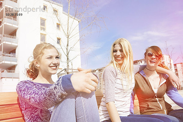 Drei Freunde sitzen auf einer Bank auf einem Spielplatz  München  Bayern  Deutschland