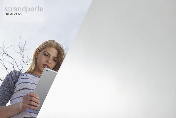Blick von unten auf ein jugendliches Mädchen  das ein digitales Tablet benutzt  München  Bayern  Deutschland