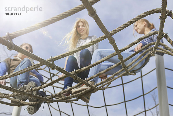 Drei Freunde sitzen auf einem Kletternetz auf einem Spielplatz  München  Bayern  Deutschland