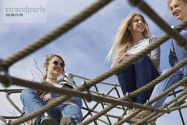 Drei Freunde sitzen auf einem Kletternetz auf einem Spielplatz  München  Bayern  Deutschland