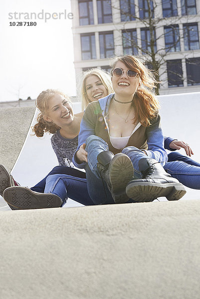 Drei Freunde rutschen die Rutsche auf einem Spielplatz hinunter  München  Bayern  Deutschland