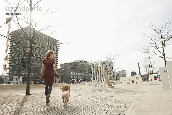 Rückansicht einer jungen Frau auf einem Spielplatz mit Hund  München  Bayern  Deutschland