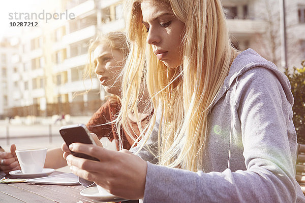 Teenager-Mädchen schreibt SMS in einem Straßencafé  München  Bayern  Deutsch