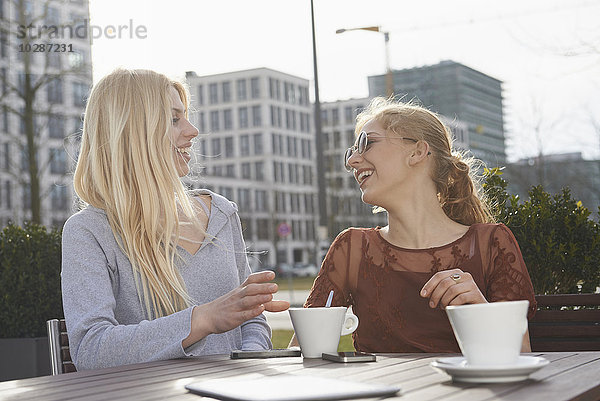 Zwei Freunde haben Spaß in einem Straßencafé  München  Bayern  Deutschland