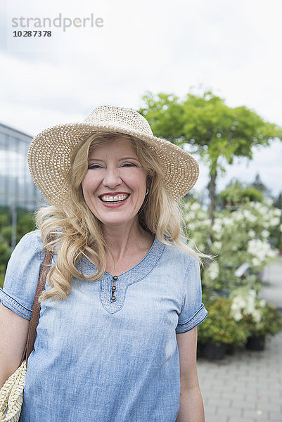 Porträt einer reifen Frau mit Hut und Lächeln in einer Gärtnerei  Augsburg  Bayern  Deutschland