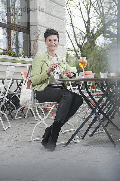 Ältere Frau trinkt Aperol Spritz in einem Straßencafé  Bayern  Deutschland