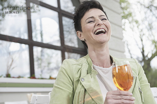 Ältere Frau lachend mit Aperol-Spritze in einem Straßencafé  Bayern  Deutschland