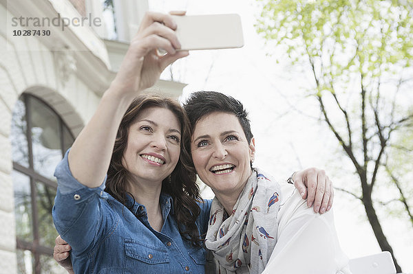 Zwei Freunde machen ein Selfie in einem Straßencafé  Bayern  Deutschland