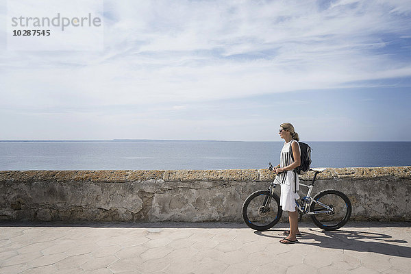 Seitenprofil einer reifen Frau mit Mountainbike an der Hafenmauer  Gallipoli  Apulien  Italien
