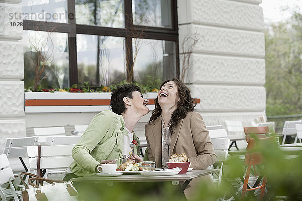 Zwei Freunde beim Frühstück in einem Straßencafé  Bayern  Deutschland