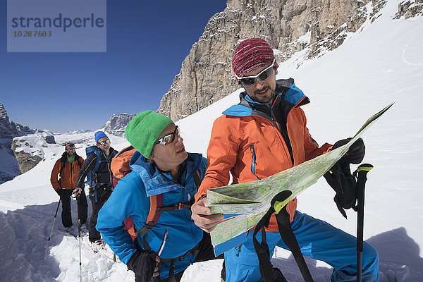Skitourengeher beim Lesen der Karte während des Aufstiegs auf einem verschneiten Berg  Gröden  Trentino-Südtirol  Italien