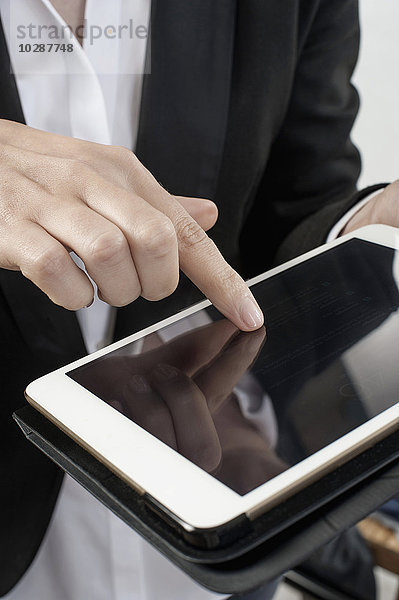 Mittelschnittansicht einer Geschäftsfrau  die ein digitales Tablet im Büro bedient  Bayern  Deutschland
