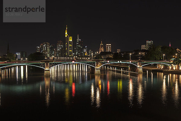 Brücke über den Fluss mit beleuchteter Skyline bei Nacht  Frankfurt  Deutschland
