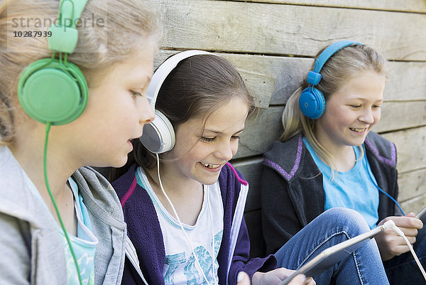 Drei Freunde sitzen auf einem Spielplatz und hören Musik  München  Bayern  Deutschland