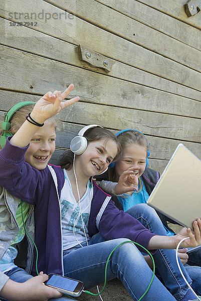 Drei Freunde sitzen auf einem Spielplatz und hören Musik  München  Bayern  Deutschland