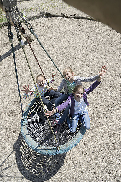 Hohe Winkelansicht von Mädchen  die auf einer Schaukel auf einem Spielplatz schaukeln  München  Bayern  Deutschland