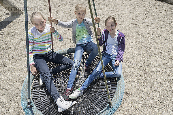 Hohe Winkelansicht von Mädchen  die auf einer Schaukel auf einem Spielplatz schaukeln  München  Bayern  Deutschland