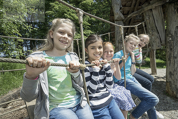Mädchen sitzen auf einer Seilbrücke auf einem Spielplatz  München  Bayern  Deutschland