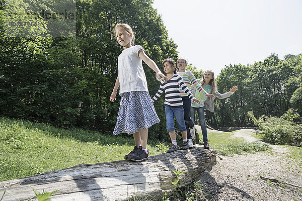 Mädchen balancieren auf einem Baumstamm auf einem Spielplatz  München  Bayern  Deutschland