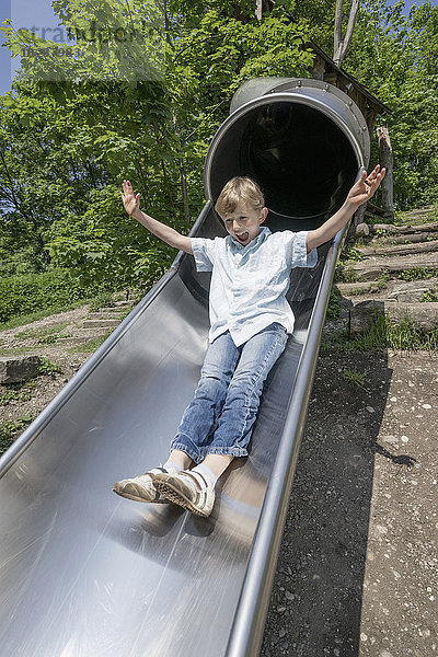 Junge rutscht auf einer Rutsche auf einem Spielplatz  München  Bayern  Deutschland