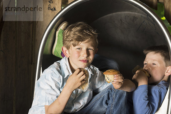 Zwei Jungen essen Muffins auf einem Spielplatz  München  Bayern  Deutschland