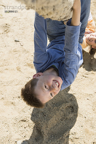 Junge und Mädchen hängen kopfüber an einem Seil auf einem Spielplatz  München  Bayern  Deutschland