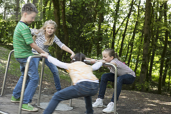 Kinder haben Spaß auf einem Karussell auf einem Spielplatz  München  Bayern  Deutschland