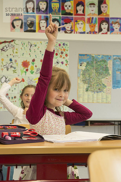 Schulkinder mit erhobenen Händen im Klassenzimmer  München  Bayern  Deutschland