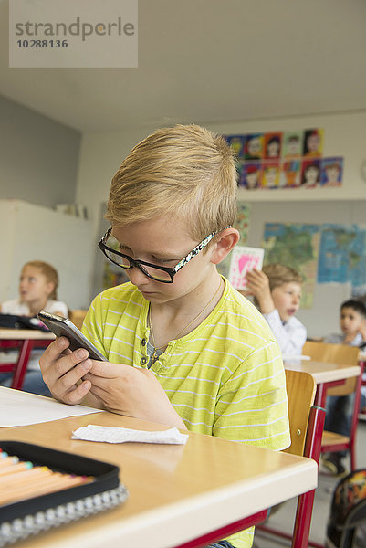 Nahaufnahme eines Schülers  der ein Smartphone im Klassenzimmer benutzt  München  Bayern  Deutschland