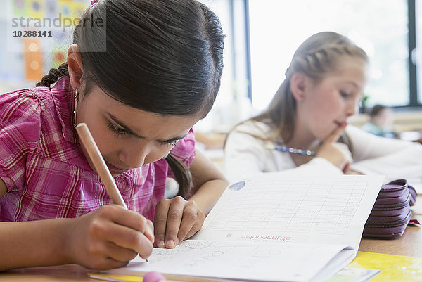 Schulmädchen  die in einem Klassenzimmer Hefte schreiben  München  Bayern  Deutschland