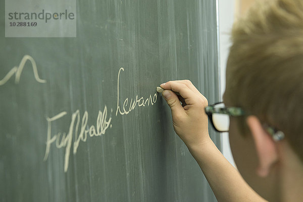 Schüler schreibt an der Tafel im Klassenzimmer  München  Bayern  Deutschland