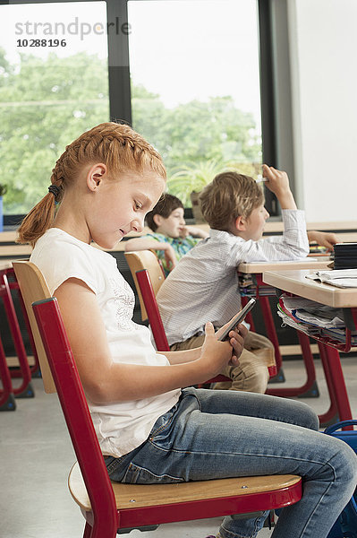 Seitenprofil einer Schülerin  die ein Smartphone im Klassenzimmer benutzt  München  Bayern  Deutschland