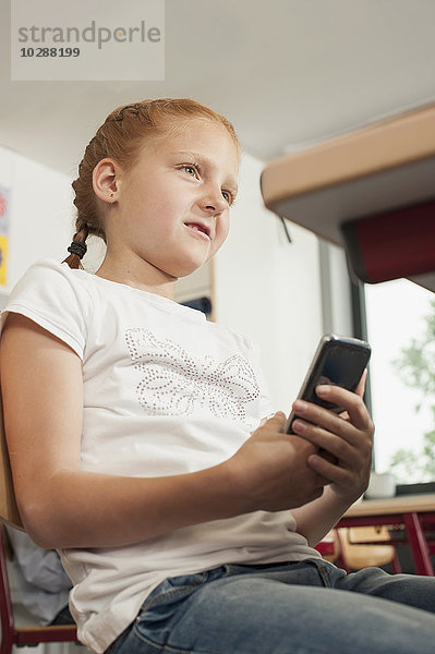 Schülerin hält ein Smartphone im Klassenzimmer  München  Bayern  Deutschland
