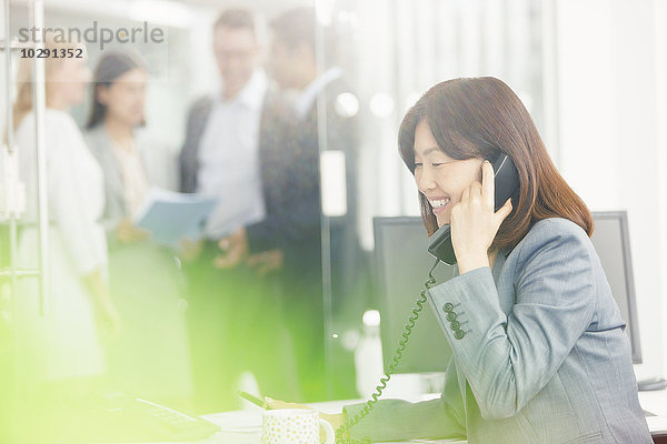 Lächelnde Geschäftsfrau am Telefon im Büro