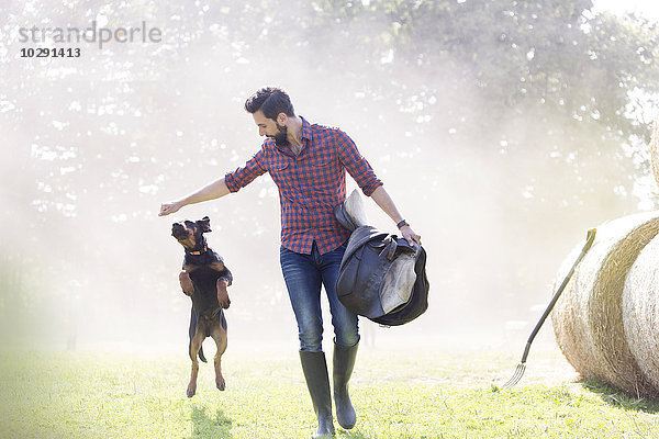 Mann mit Sattelschritt mit springendem Hund