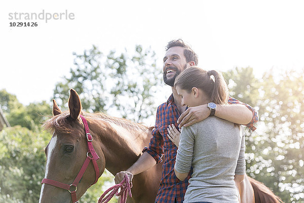 Lächelndes Paar umarmt das Pferd