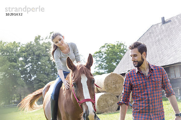 Mann führende Frau beim Reiten auf ländlicher Weide