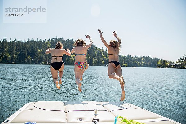 Rückansicht von drei jungen Frauen beim Sprung vom Pier  Lake Oswego  Oregon  USA