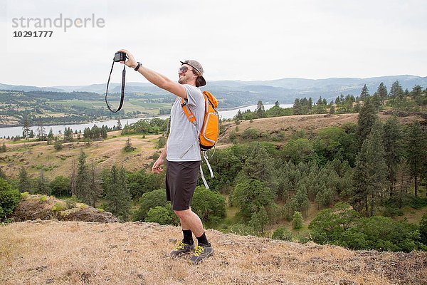 Junger Mann  auf dem Berg stehend  Selbstporträt mit Kamera aufnehmend