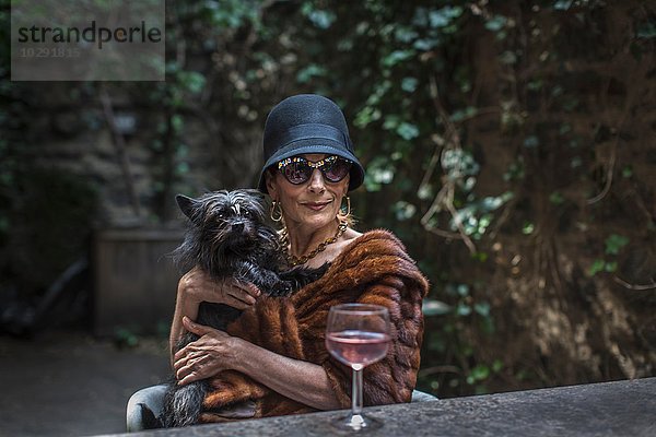 Modische Seniorin mit Hund im Garten