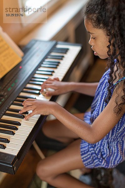 Hochwinklige Seitenansicht des Mädchens beim Keyboarden