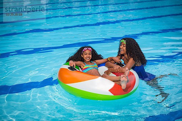 Mädchen im Schwimmbad spielen mit aufblasbarem Ring  lächelnd