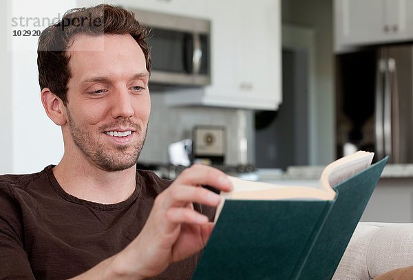 Mittlerer Erwachsener Mann zu Hause sitzend  Lesebuch