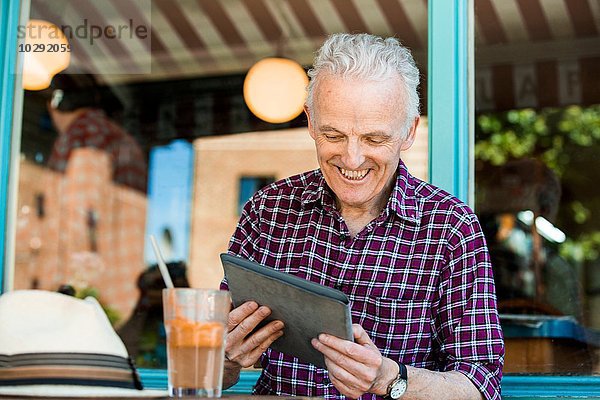 Senior Mann mit digitalem Tablett im Cafe