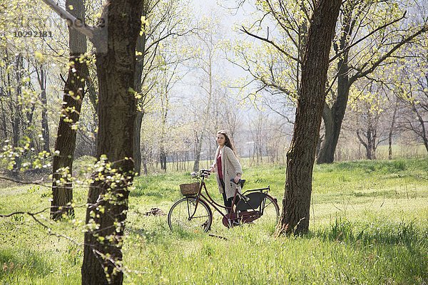 Porträt einer jungen Frau mit Fahrrad im ländlichen Wald