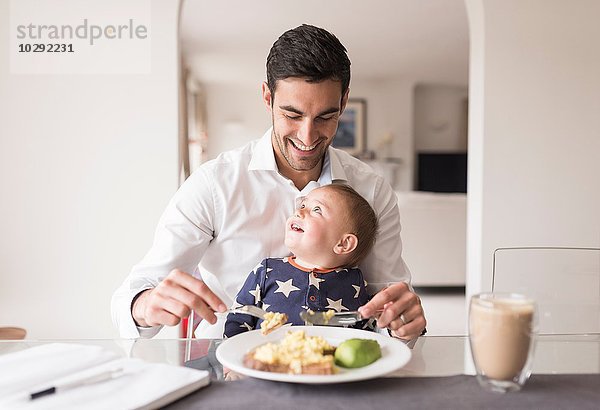 Vater beim Essen mit dem kleinen Sohn auf dem Schoß