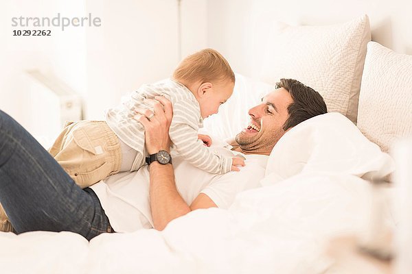 Vater und kleiner Sohn entspannen sich gemeinsam auf dem Bett  lachend